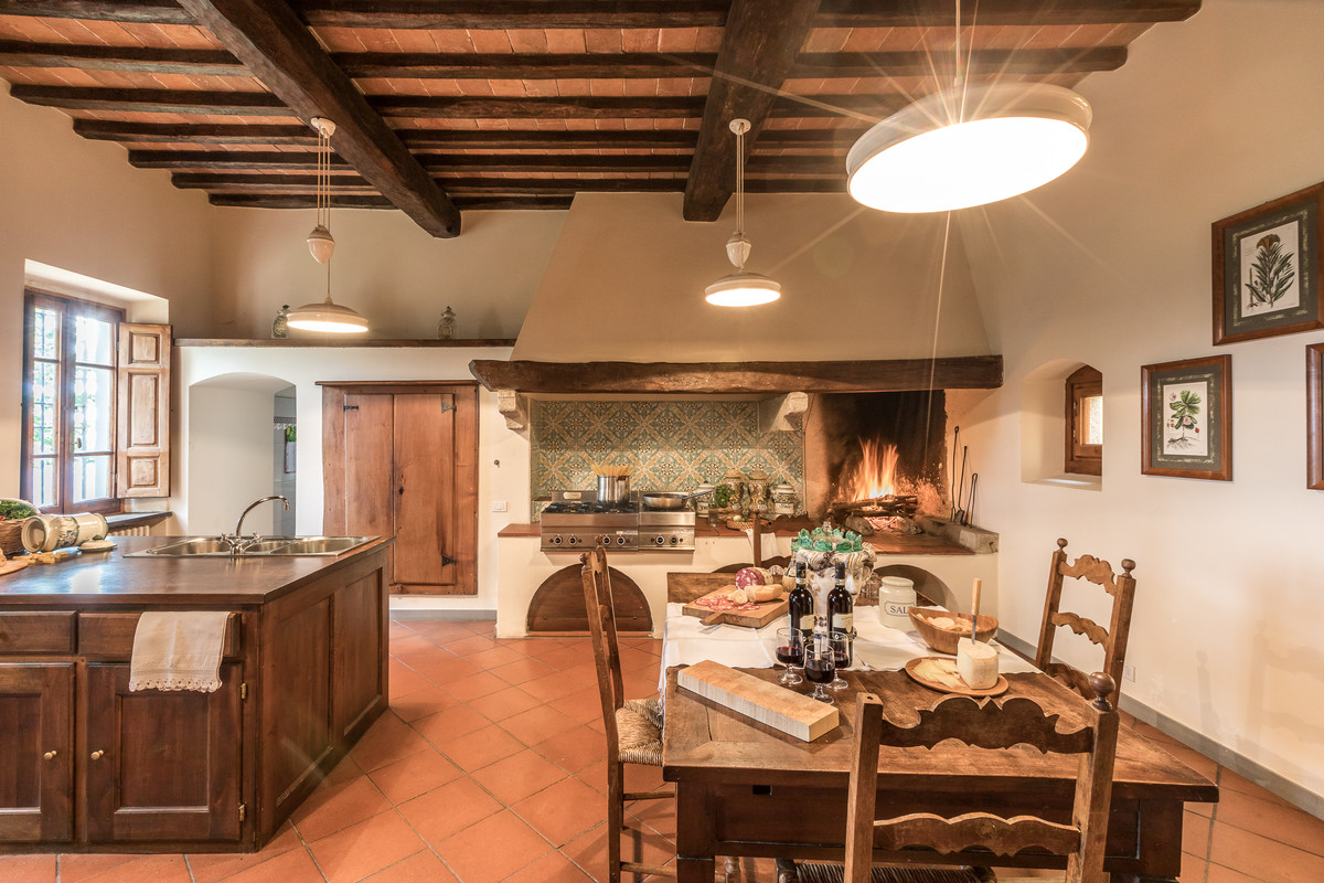 Photo of a large country single-wall eat-in kitchen in Florence with a triple-bowl sink, recessed-panel cabinets, dark wood cabinets, multi-coloured splashback, ceramic splashback, stainless steel appliances, terra-cotta floors, with island and red floor.
