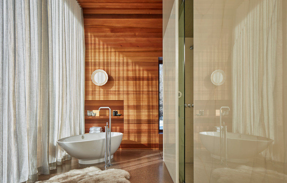 他の地域にあるコンテンポラリースタイルのおしゃれなマスターバスルーム (置き型浴槽、コンクリートの床、板張り壁) の写真