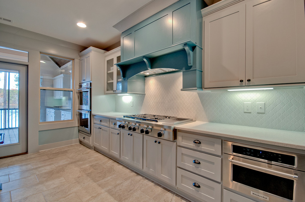 Large transitional single-wall porcelain tile and multicolored floor open concept kitchen photo with a farmhouse sink, shaker cabinets, gray cabinets, quartz countertops, white backsplash, ceramic backsplash, stainless steel appliances, an island and white countertops