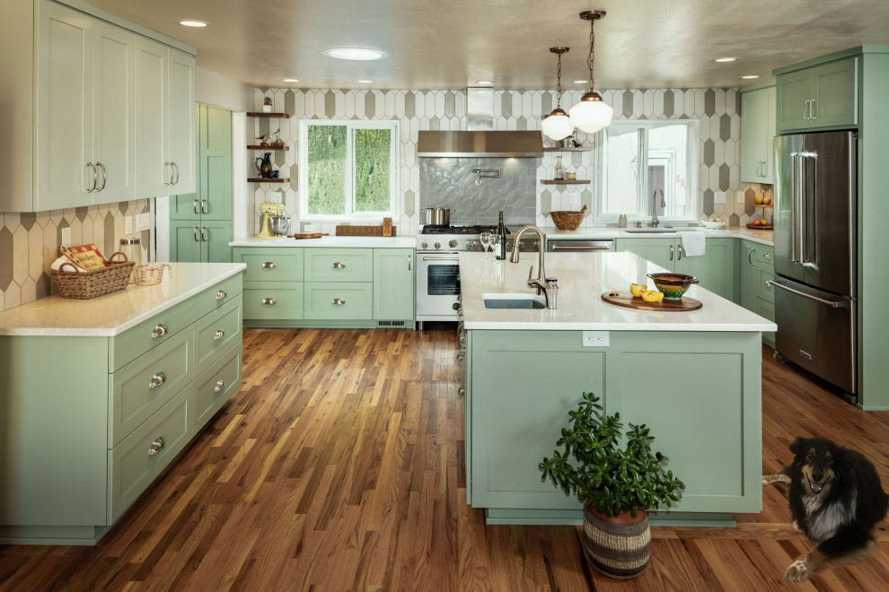 Large transitional l-shaped medium tone wood floor eat-in kitchen photo with an undermount sink, shaker cabinets, green cabinets, quartz countertops, gray backsplash, ceramic backsplash, stainless steel appliances, an island and white countertops