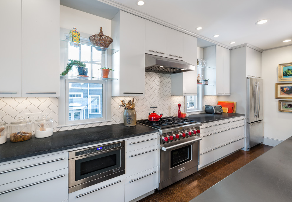 Foto på ett mellanstort funkis svart linjärt kök med öppen planlösning, med en integrerad diskho, vitt stänkskydd, stänkskydd i keramik, rostfria vitvaror, korkgolv, en köksö, brunt golv, vita skåp och bänkskiva i kvarts