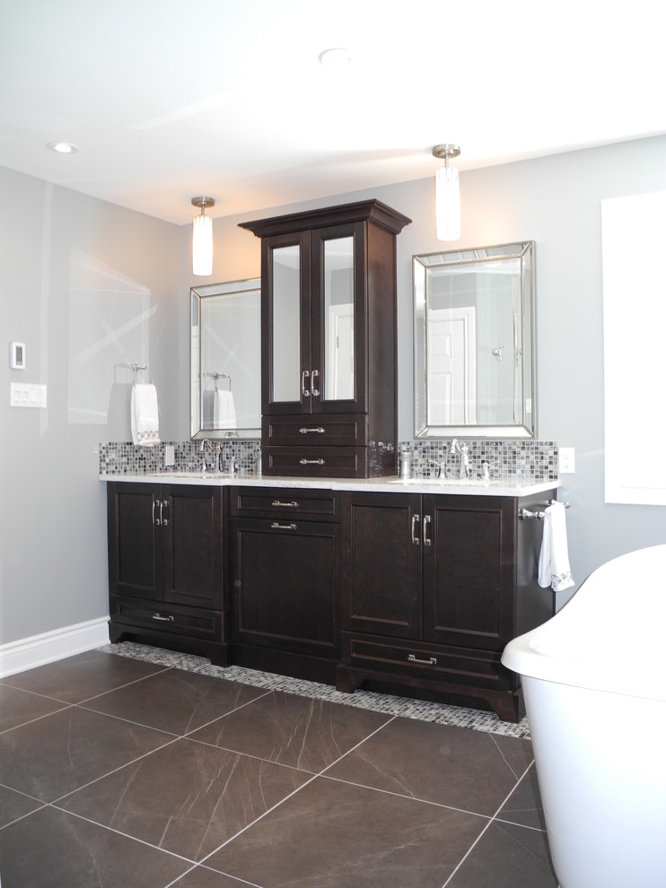 Design ideas for a mid-sized contemporary master bathroom in Ottawa with an integrated sink, beaded inset cabinets, dark wood cabinets, quartzite benchtops, a freestanding tub, a one-piece toilet, gray tile, glass tile, grey walls, ceramic floors and a corner shower.