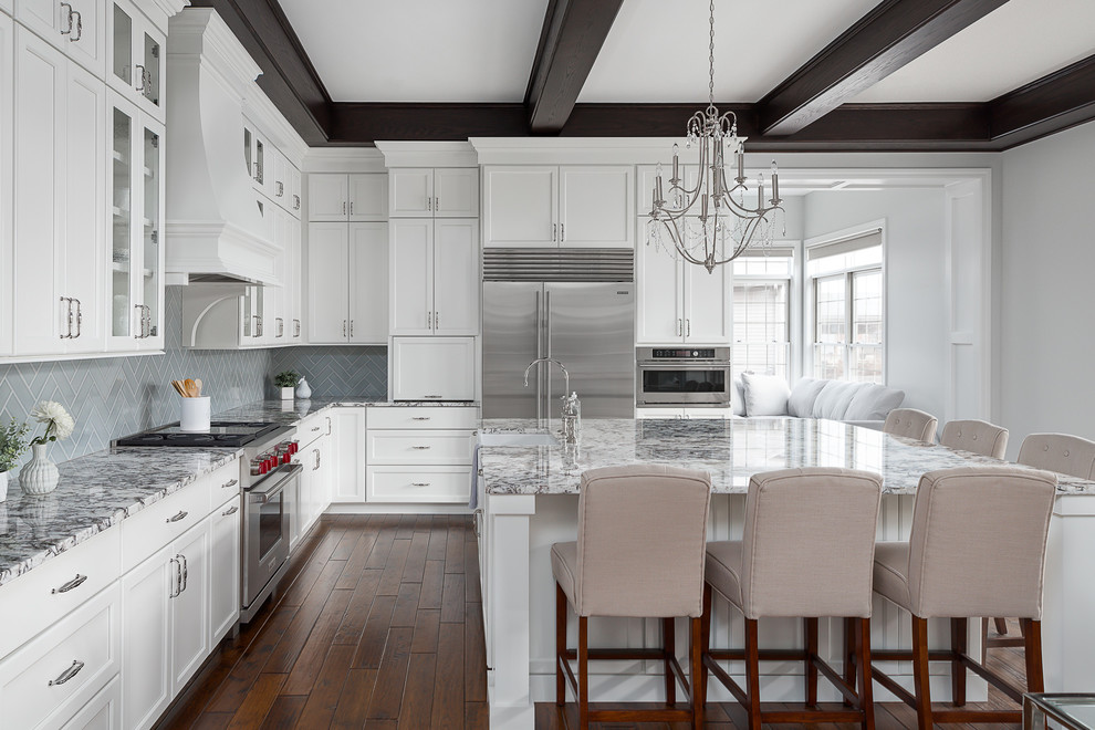 Inspiration for a large transitional l-shaped eat-in kitchen in Chicago with a farmhouse sink, white cabinets, granite benchtops, porcelain splashback, stainless steel appliances, dark hardwood floors, with island, brown floor and multi-coloured benchtop.