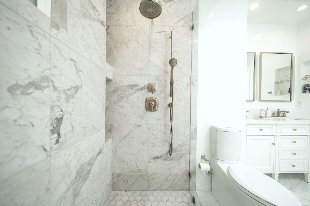 This is an example of a large classic grey and white ensuite bathroom in Los Angeles with shaker cabinets, white cabinets, a walk-in shower, a two-piece toilet, multi-coloured tiles, marble tiles, white walls, marble flooring, a submerged sink, engineered stone worktops, multi-coloured floors, a hinged door, white worktops, a wall niche, double sinks and a freestanding vanity unit.