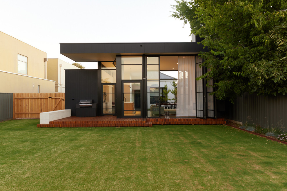 Immagine della villa nera contemporanea a un piano di medie dimensioni con rivestimento con lastre in cemento, tetto piano, copertura in metallo o lamiera e tetto nero