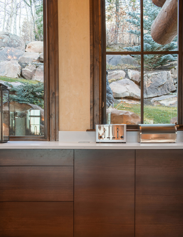 Example of a large minimalist l-shaped orange floor eat-in kitchen design in Denver with flat-panel cabinets, dark wood cabinets, quartzite countertops, beige backsplash, stone slab backsplash, stainless steel appliances, an island, white countertops and an undermount sink