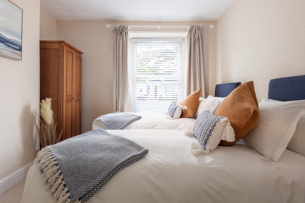 Imagen de habitación de invitados costera pequeña sin chimenea con paredes beige, moqueta y suelo beige