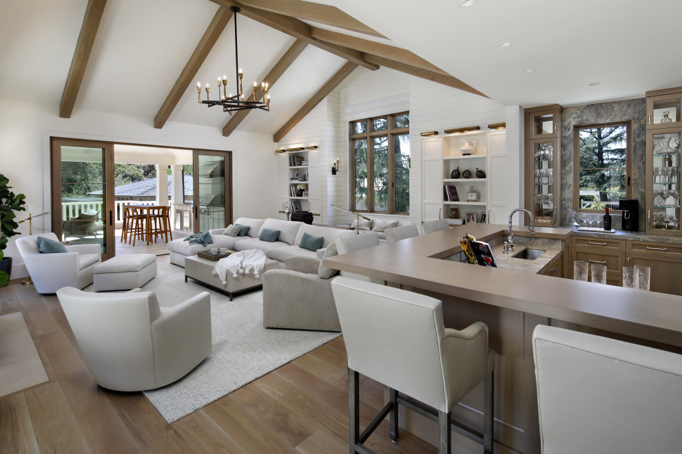 This is an example of a rural games room in San Francisco with a home bar, white walls, light hardwood flooring, a standard fireplace, a stone fireplace surround, brown floors, exposed beams and tongue and groove walls.