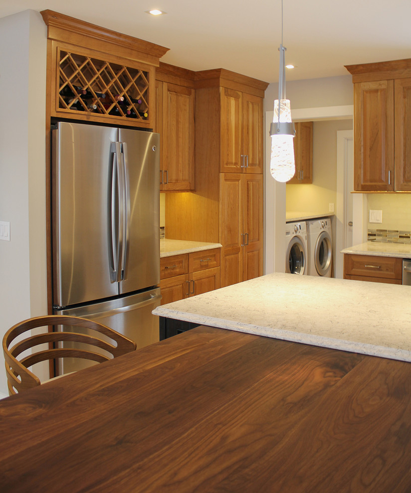Open concept kitchen - large transitional u-shaped light wood floor and beige floor open concept kitchen idea in Boston with an undermount sink, raised-panel cabinets, medium tone wood cabinets, quartz countertops, multicolored backsplash, glass tile backsplash, stainless steel appliances, an island and beige countertops