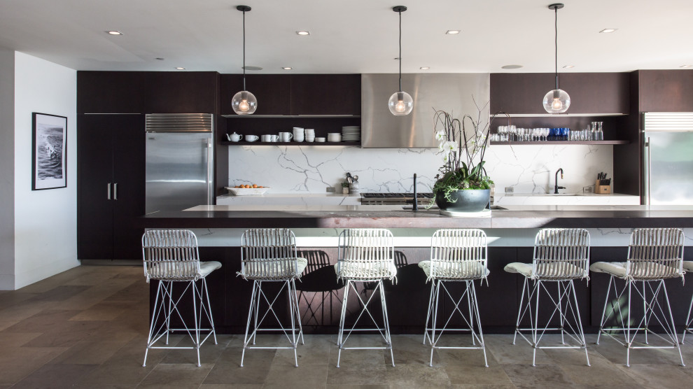 Inspiration for a large contemporary open plan kitchen in Los Angeles with a drop-in sink, flat-panel cabinets, dark wood cabinets, marble benchtops, white splashback, marble splashback, stainless steel appliances, porcelain floors, with island, beige floor and white benchtop.