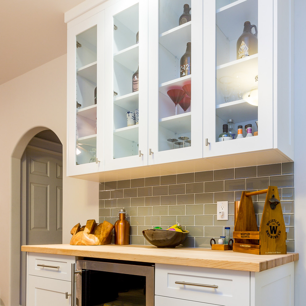 Large transitional u-shaped light wood floor open concept kitchen photo with a farmhouse sink, shaker cabinets, blue cabinets, quartz countertops, gray backsplash, glass tile backsplash, stainless steel appliances and an island