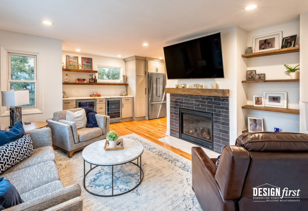 Mid-sized contemporary enclosed family room in Chicago with a home bar, grey walls, light hardwood floors, a standard fireplace, a tile fireplace surround, a wall-mounted tv and brown floor.