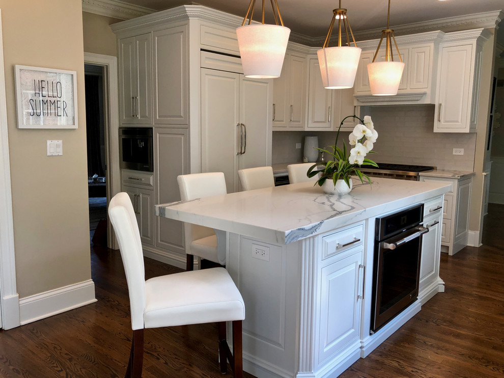 Eat-in kitchen - large transitional u-shaped dark wood floor and brown floor eat-in kitchen idea in Chicago with an undermount sink, raised-panel cabinets, white cabinets, quartz countertops, gray backsplash, ceramic backsplash, stainless steel appliances, an island and white countertops