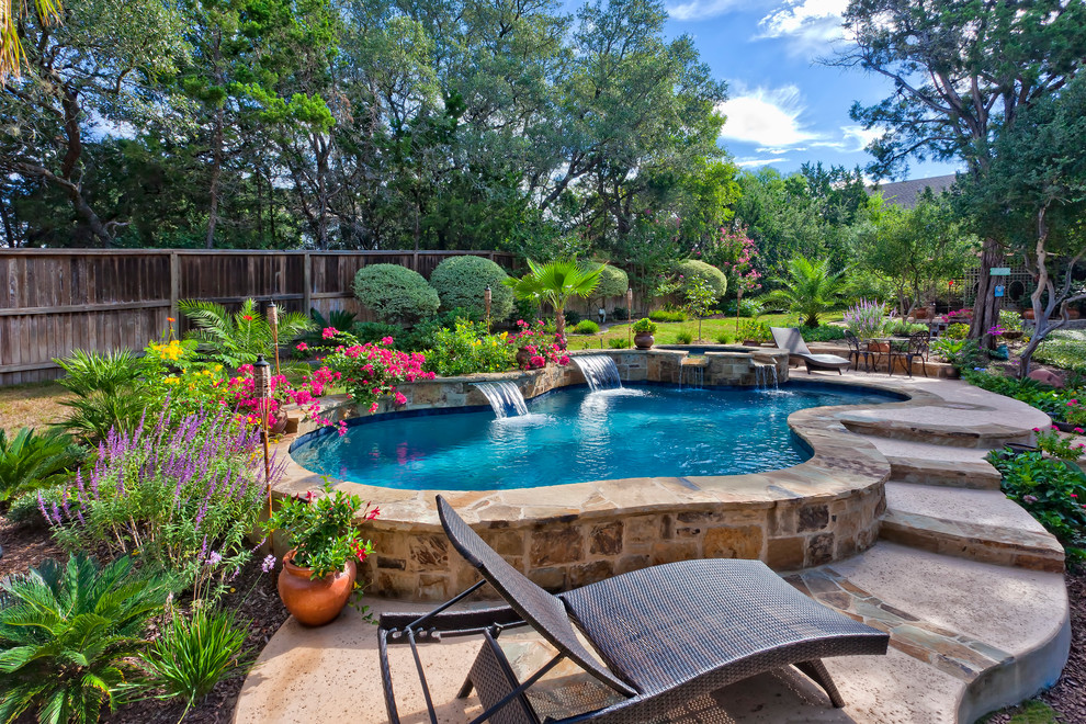 Photo of a mid-sized traditional backyard custom-shaped natural pool in Austin with a hot tub and natural stone pavers.