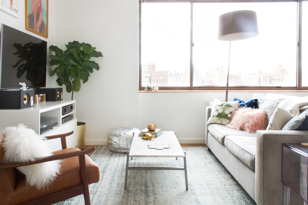 Example of a small trendy loft-style medium tone wood floor and brown floor living room design in New York with white walls, no fireplace and a tv stand