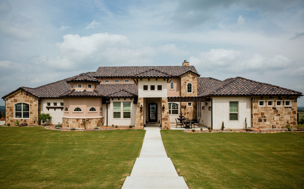 Design ideas for an expansive mediterranean two-storey brick beige house exterior in Dallas with a hip roof and a tile roof.