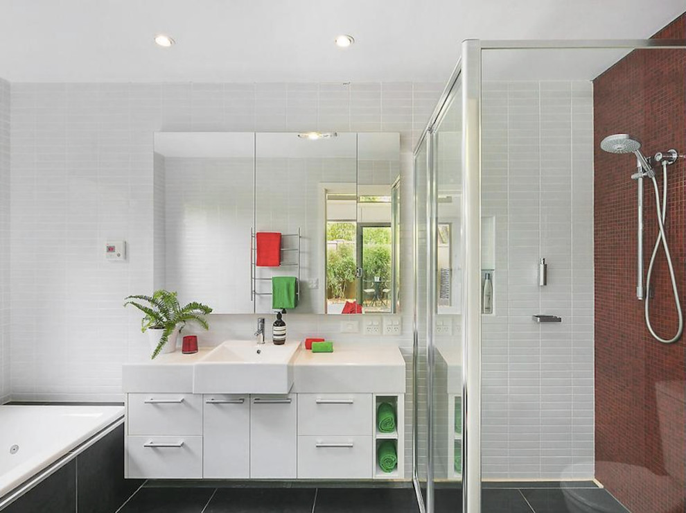 Photo of a mid-sized contemporary master bathroom in Canberra - Queanbeyan with flat-panel cabinets, white cabinets, an alcove tub, a corner shower, red tile, white tile, ceramic floors, an integrated sink, black floor, a hinged shower door, a one-piece toilet, ceramic tile, white walls and laminate benchtops.