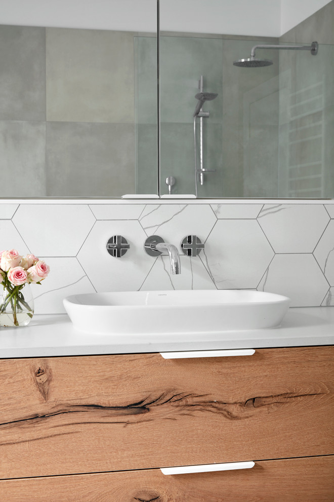 Design ideas for a large contemporary master bathroom in Melbourne with flat-panel cabinets, light wood cabinets, a freestanding tub, an open shower, gray tile, white tile, mosaic tile, white walls, mosaic tile floors, a vessel sink and solid surface benchtops.