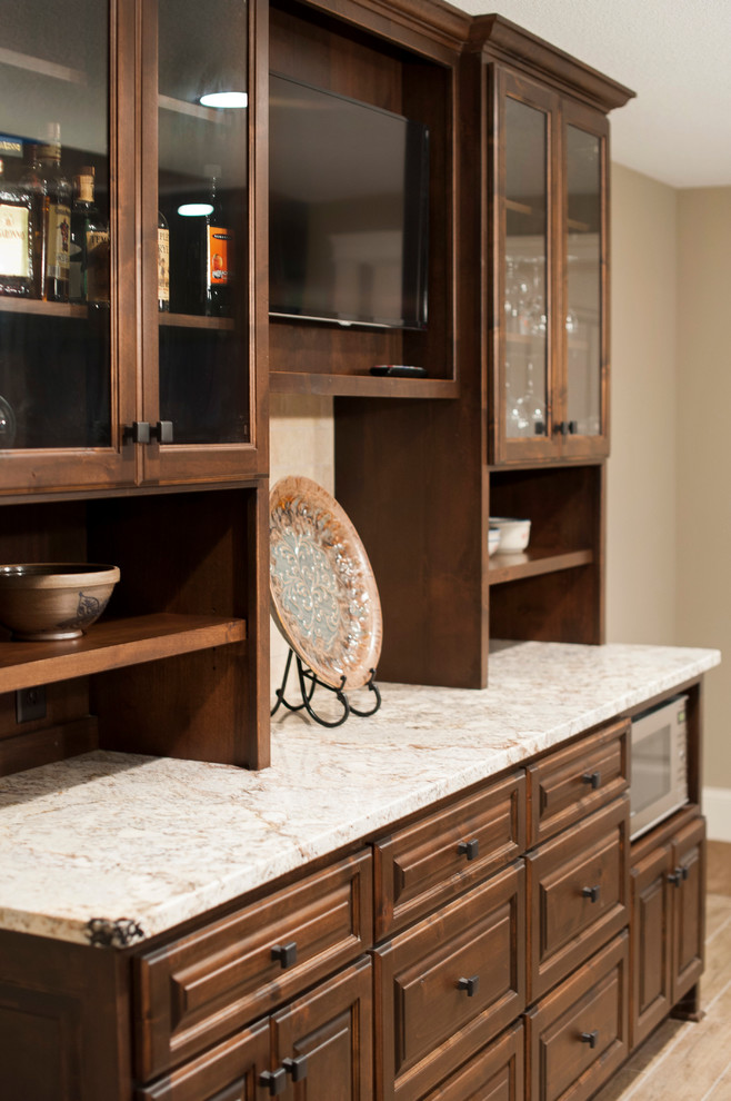 Photo of a mid-sized arts and crafts u-shaped wet bar in Minneapolis with an undermount sink, raised-panel cabinets, dark wood cabinets, granite benchtops, brown splashback, travertine splashback and ceramic floors.