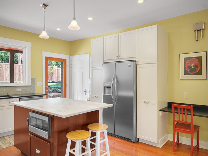 Mid-sized traditional l-shaped eat-in kitchen in Seattle with an undermount sink, shaker cabinets, white cabinets, marble benchtops, grey splashback, subway tile splashback, stainless steel appliances, medium hardwood floors, with island, brown floor and white benchtop.