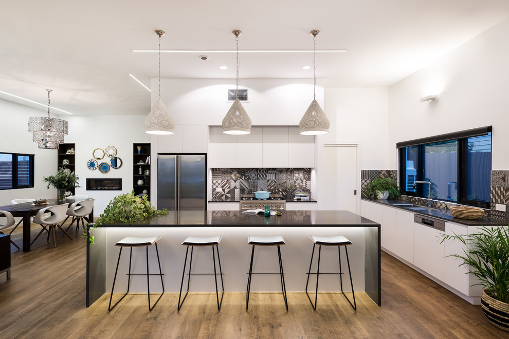 Inspiration for a contemporary galley open plan kitchen in Melbourne with an undermount sink, flat-panel cabinets, white cabinets, quartz benchtops, multi-coloured splashback, porcelain splashback, stainless steel appliances, porcelain floors, with island, brown floor and black benchtop.
