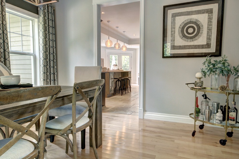 Example of a mid-sized transitional light wood floor and brown floor enclosed dining room design with gray walls, a two-sided fireplace and a stone fireplace