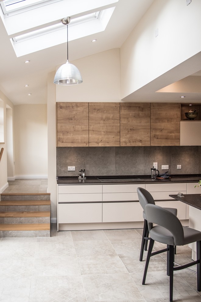 Design ideas for a large contemporary l-shaped eat-in kitchen in London with an integrated sink, flat-panel cabinets, medium wood cabinets, granite benchtops, grey splashback, cement tile splashback, black appliances, cement tiles, with island and grey floor.
