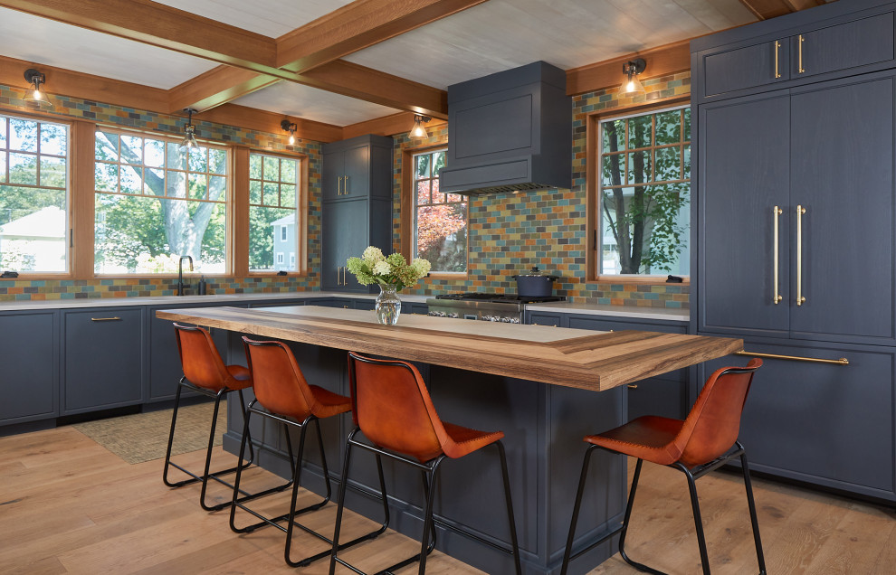Inspiration for a large arts and crafts l-shaped eat-in kitchen in Grand Rapids with an undermount sink, shaker cabinets, blue cabinets, wood benchtops, multi-coloured splashback, subway tile splashback, panelled appliances, medium hardwood floors, with island and coffered.