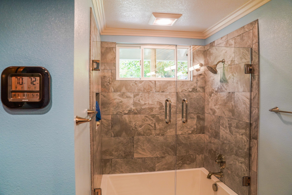 Cette photo montre une salle de bain principale chic de taille moyenne avec un combiné douche/baignoire, un lavabo posé, un plan de toilette en marbre, une cabine de douche à porte battante, un plan de toilette beige et meuble double vasque.