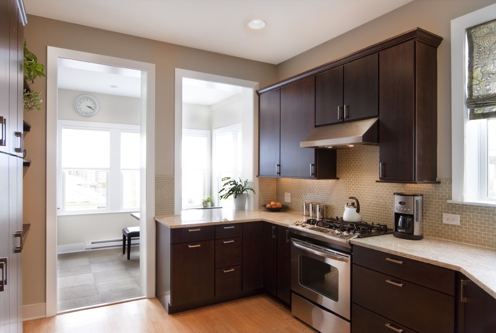 Inspiration for a small modern l-shaped separate kitchen in Chicago with a drop-in sink, flat-panel cabinets, limestone benchtops, brown splashback, glass tile splashback, stainless steel appliances and light hardwood floors.