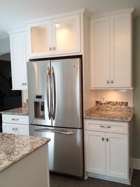 Example of a mid-sized transitional u-shaped eat-in kitchen design with an undermount sink, shaker cabinets, white cabinets, quartz countertops, white backsplash, porcelain backsplash, stainless steel appliances and an island