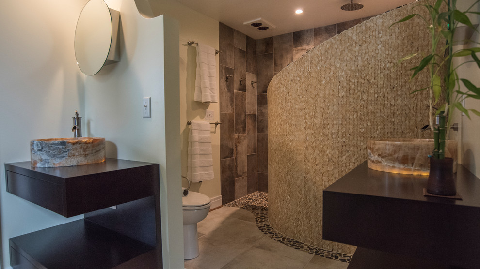 Photo of a mid-sized modern master bathroom in New York with a vessel sink, flat-panel cabinets, dark wood cabinets, wood benchtops, an open shower, a one-piece toilet, beige tile, glass sheet wall, beige walls and marble floors.