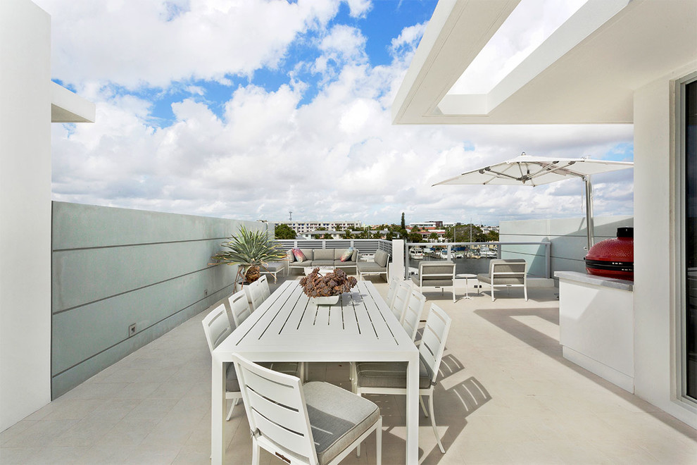 Photo of a mid-sized modern rooftop deck in Miami with an outdoor kitchen and a roof extension.