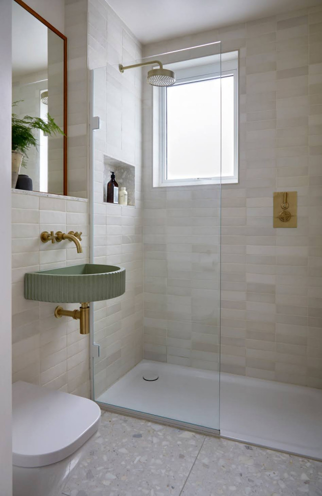 Modern inredning av ett badrum, med en öppen dusch, en vägghängd toalettstol, keramikplattor, terrazzogolv och bänkskiva i terrazo