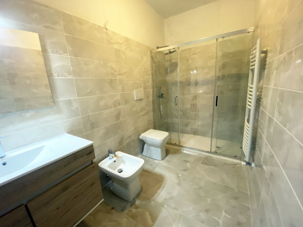 Exemple d'un grand WC et toilettes avec WC séparés, un carrelage beige, des carreaux de porcelaine, un mur blanc, un sol en carrelage de porcelaine et un sol beige.