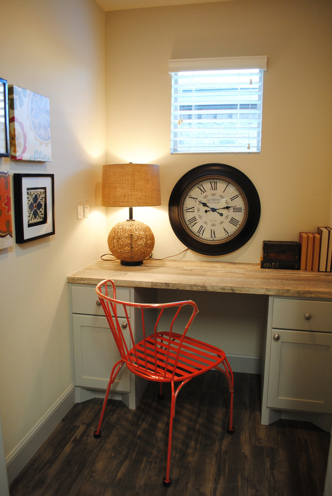 This is an example of a small eclectic study room in Austin with beige walls, vinyl floors and a built-in desk.