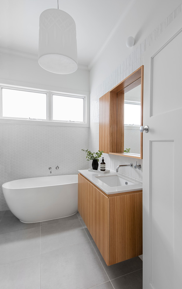Design ideas for a mid-sized contemporary kids bathroom in Melbourne with medium wood cabinets, a freestanding tub, white tile, subway tile, porcelain floors, an undermount sink, engineered quartz benchtops, grey floor, a hinged shower door and white benchtops.