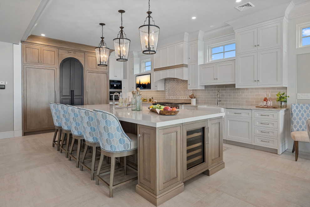 Inspiration for a large beach style open plan kitchen in New York with a farmhouse sink, shaker cabinets, white cabinets, quartzite benchtops, beige splashback, mosaic tile splashback, stainless steel appliances, porcelain floors, with island, beige floor and white benchtop.