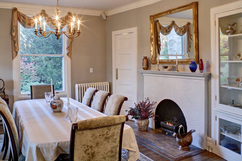 Inspiration for a traditional separate dining room in New York with a standard fireplace, a brick fireplace surround, beige walls and dark hardwood floors.