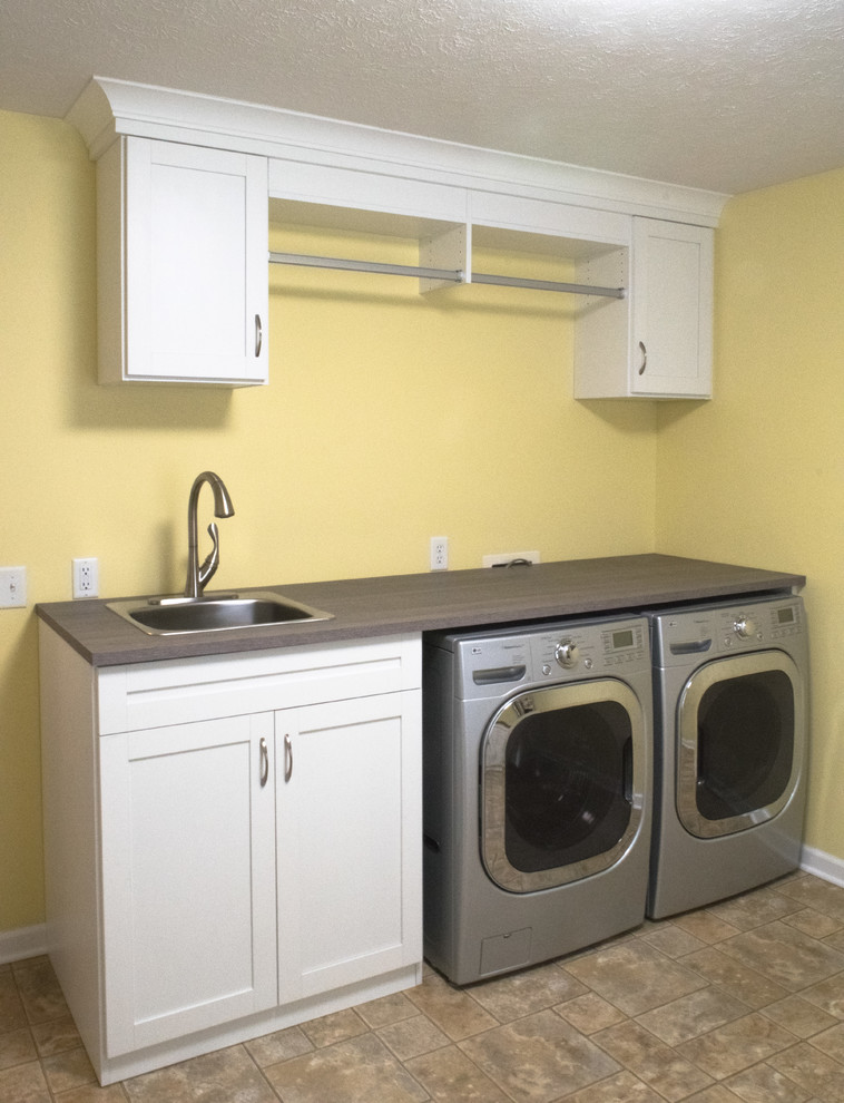 Inspiration for a mid-sized transitional utility room in Indianapolis with a drop-in sink, shaker cabinets, white cabinets, laminate benchtops, yellow walls, linoleum floors, a side-by-side washer and dryer and brown floor.