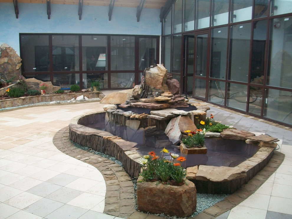 This is an example of a traditional rooftop natural pool in Other with natural stone pavers.