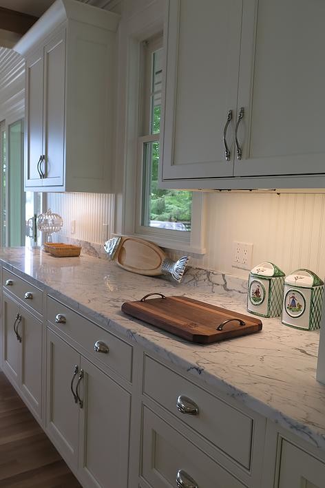 Inspiration for a mid-sized timeless l-shaped light wood floor eat-in kitchen remodel with an undermount sink, shaker cabinets, white cabinets, white backsplash, stone tile backsplash, stainless steel appliances, an island and marble countertops