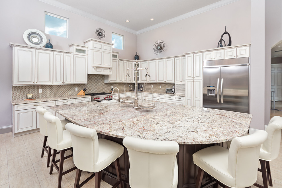 Large transitional l-shaped ceramic tile and beige floor kitchen photo in Orlando with a farmhouse sink, raised-panel cabinets, white cabinets, granite countertops, mosaic tile backsplash, stainless steel appliances, an island and beige backsplash