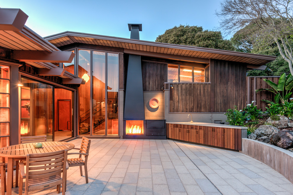Photo of a large midcentury backyard patio in San Francisco with no cover, with fireplace and concrete pavers.