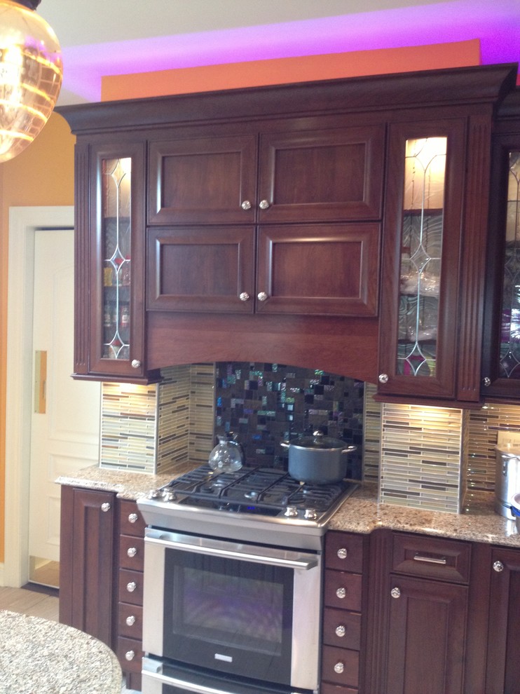 Example of a large transitional u-shaped porcelain tile home design design in Newark with a farmhouse sink, recessed-panel cabinets, red cabinets, granite countertops, beige backsplash, mosaic tile backsplash, stainless steel appliances and an island