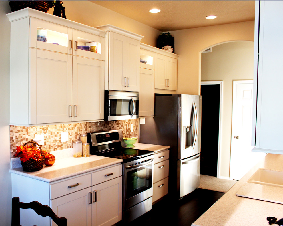Example of a transitional galley eat-in kitchen design in Boise with an integrated sink, shaker cabinets, white cabinets, solid surface countertops, beige backsplash, glass tile backsplash and stainless steel appliances
