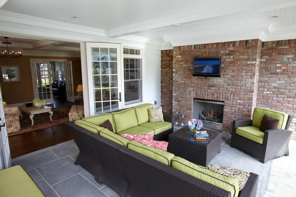 This is an example of a large beach style open concept living room in New York with a standard fireplace, a brick fireplace surround and a wall-mounted tv.