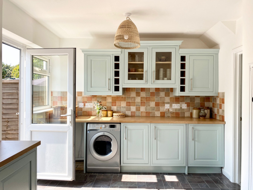 This is an example of a mid-sized country l-shaped eat-in kitchen in Gloucestershire with a drop-in sink, shaker cabinets, blue cabinets, wood benchtops, multi-coloured splashback, ceramic splashback, stainless steel appliances, linoleum floors, no island, grey floor and beige benchtop.