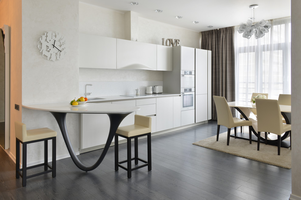 Contemporary single-wall eat-in kitchen in Moscow with flat-panel cabinets, white cabinets, white splashback, white appliances and dark hardwood floors.