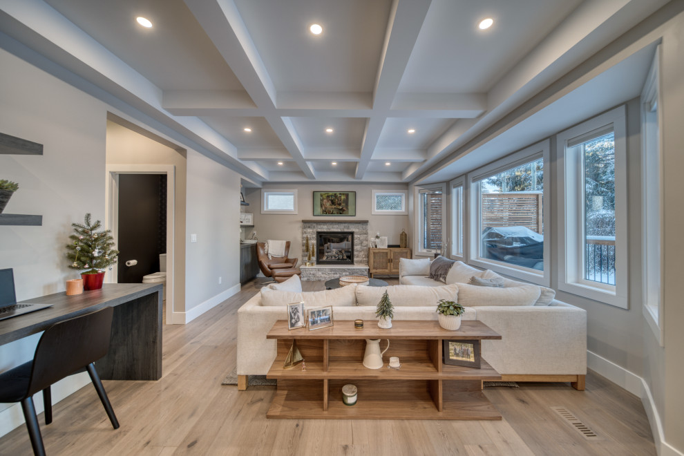 This is an example of a kitchen/dining combo in Calgary with beige walls, light hardwood floors, beige floor, a standard fireplace, a stone fireplace surround and coffered.